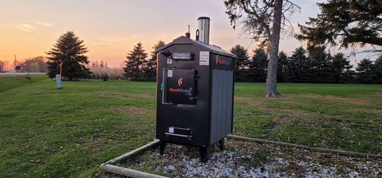 A HeatMaster stainless steel outdoor boiler at sunset