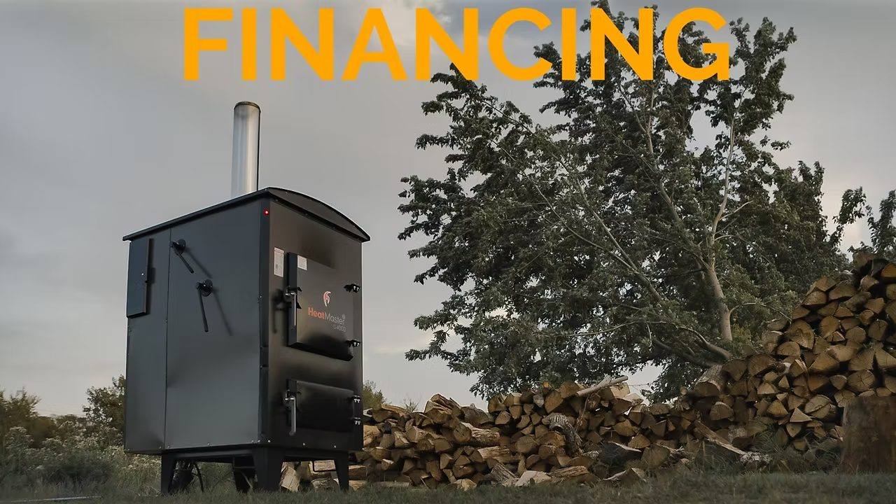 HeatMaster financing: a G4000 outdoor wood boiler beside a woodpile