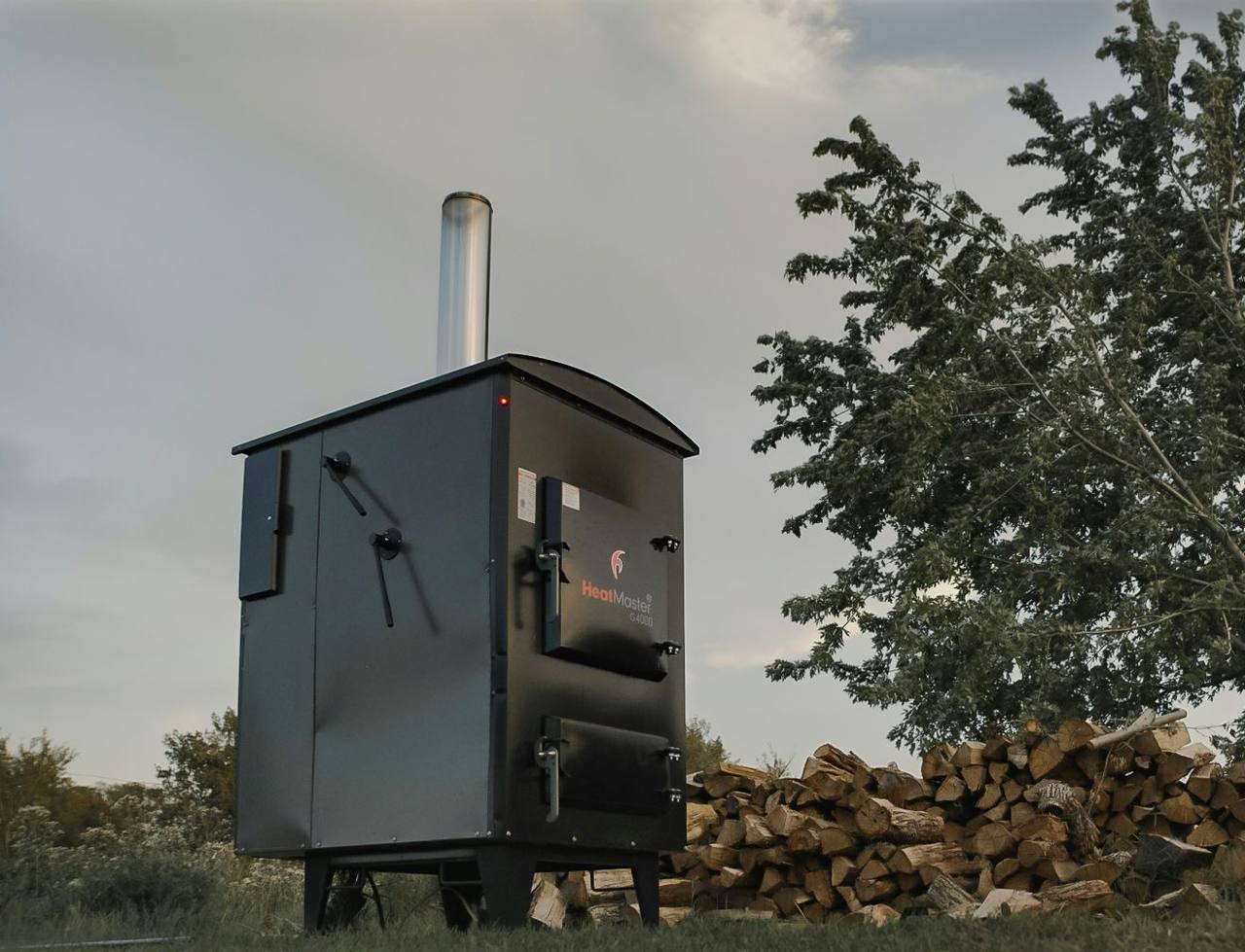 A HeatMaster G4000 beside a stack of firewood